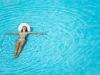 Girl with hat swimming in crystal-clear pool